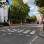 Beatles in London: Orte abseits von Abbey Road Abbey Road Zebrastreifen in London mit unscharfen Passanten und Abbey Road Studios im Hintergrund